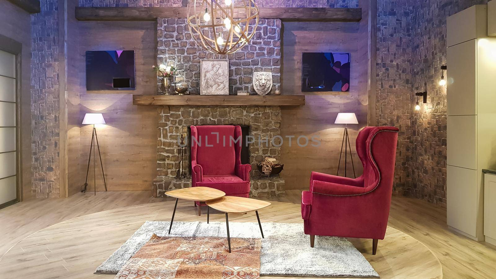 Ukraine, Kiev - June 10, 2020. Modern living room of a large house with a kitchen, fireplace, green sofa and red soft chairs, steps to the second floor, ice lights and lamps, decoration elements.