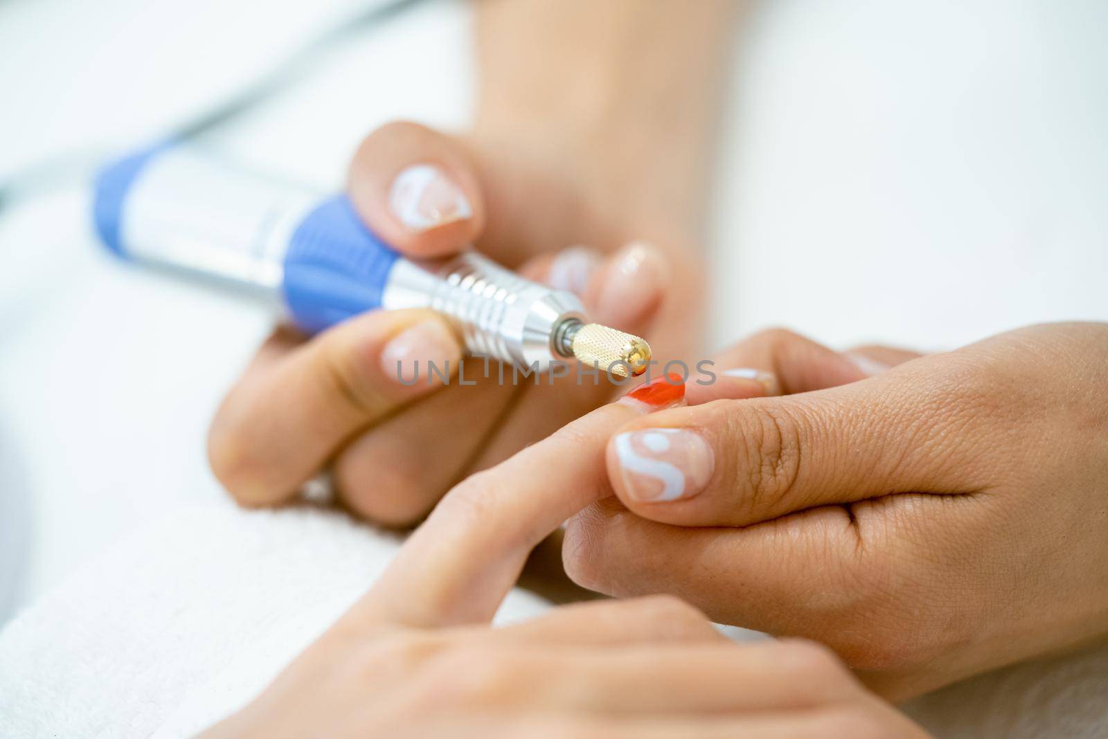 Woman in a nail salon receiving a manicure by a beautician with. by javiindy