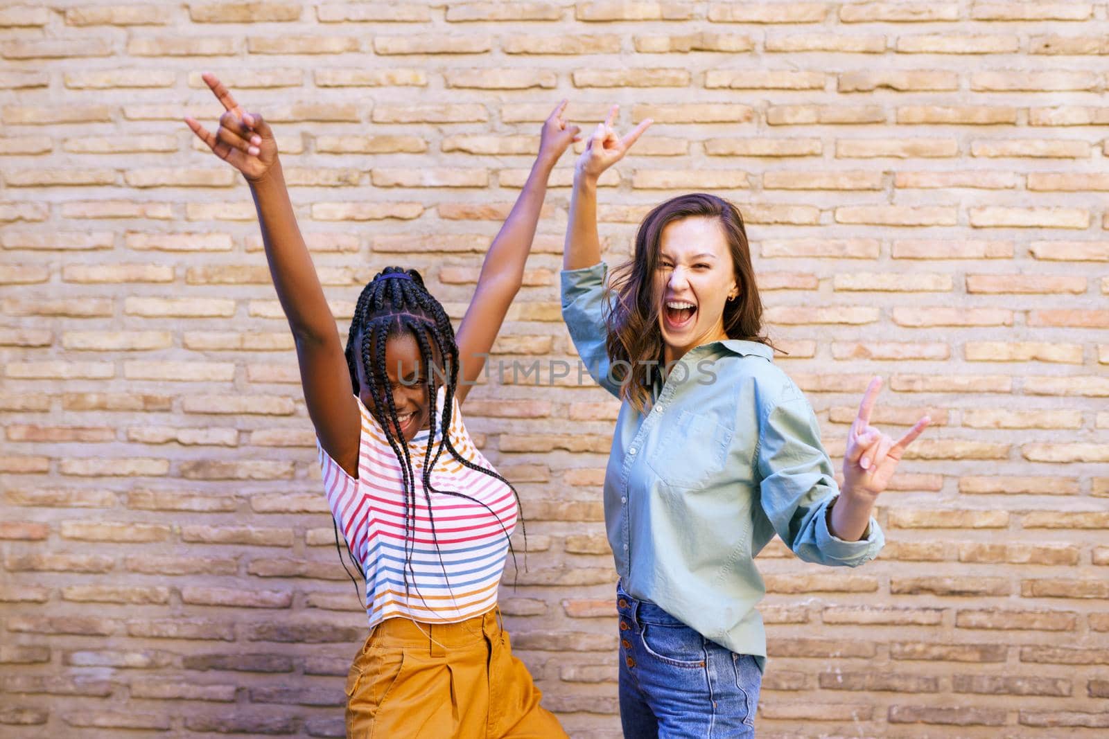 Two female friends having fun together on the street. Multiethnic friends. by javiindy