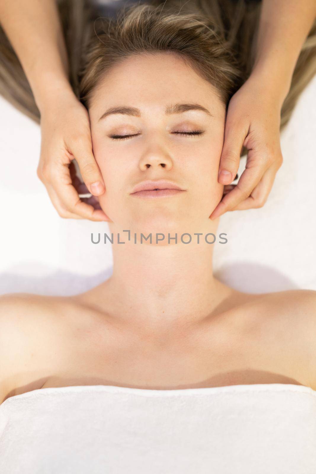 Young blond woman receiving a head massage in a spa center. by javiindy