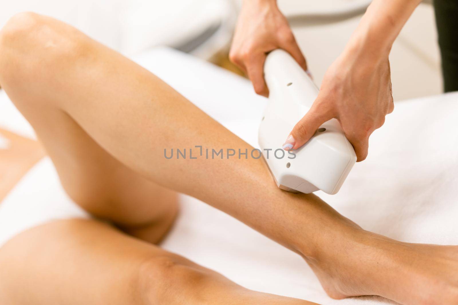 Beautiful woman receiving legs laser hair removal at a beauty center.