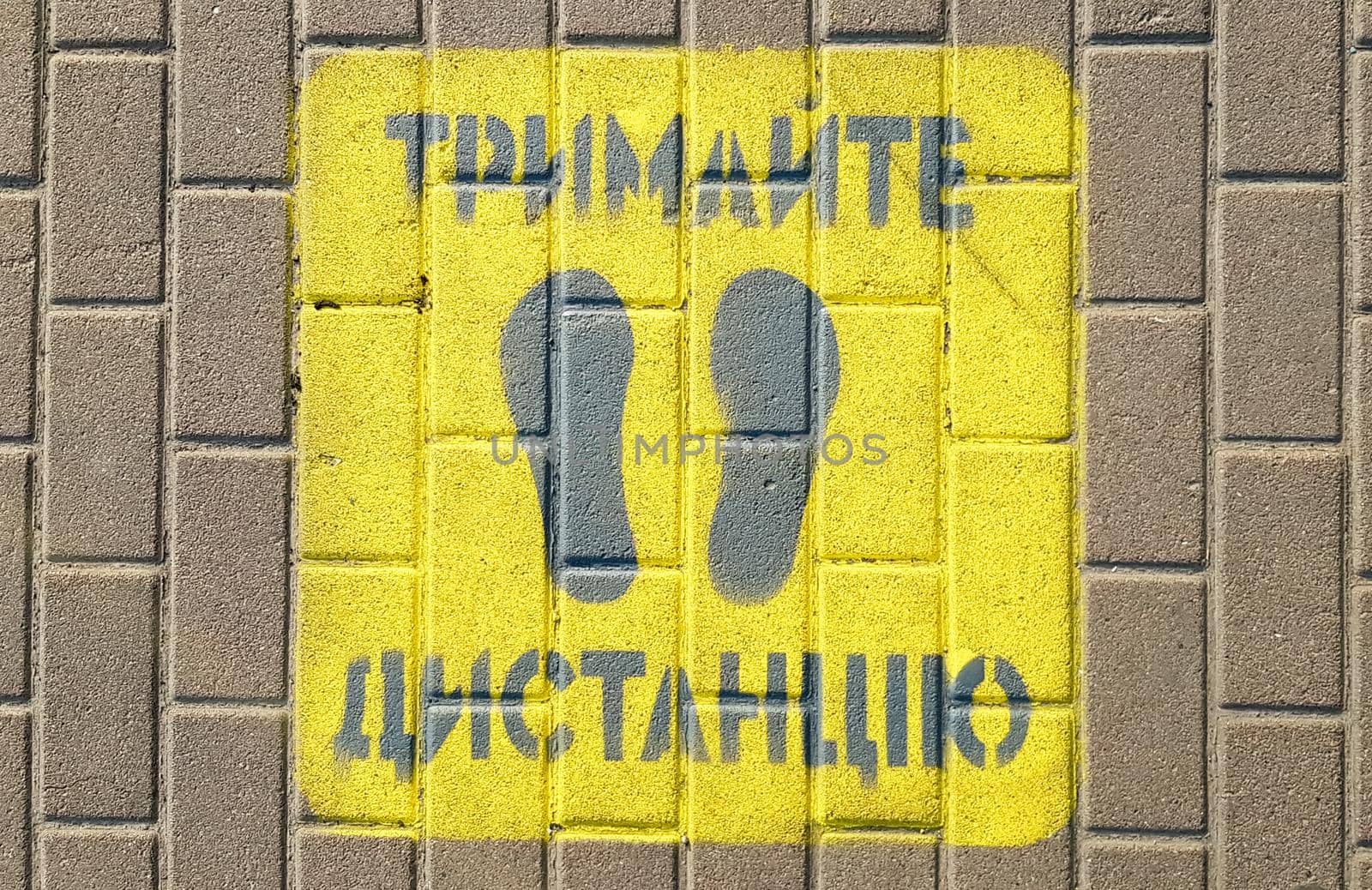 Ukraine, Kiev - April 23, 2020. Yellow sidewalk with the warning Keep your distance on the sidewalk. The text is in Ukrainian. Concept of maintaining social distance, quarantine or isolation by Roshchyn