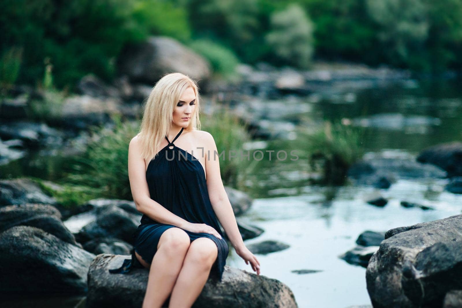 blonde girl in a black dress with blue eyes on the coast of the river by Andreua