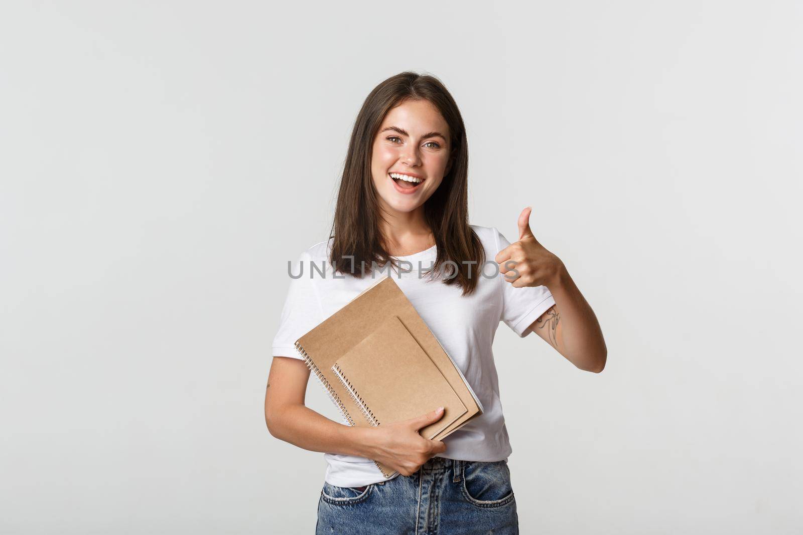 Cheerful smiling girl holding notebooks and showing thumbs-up, recommend courses or school.