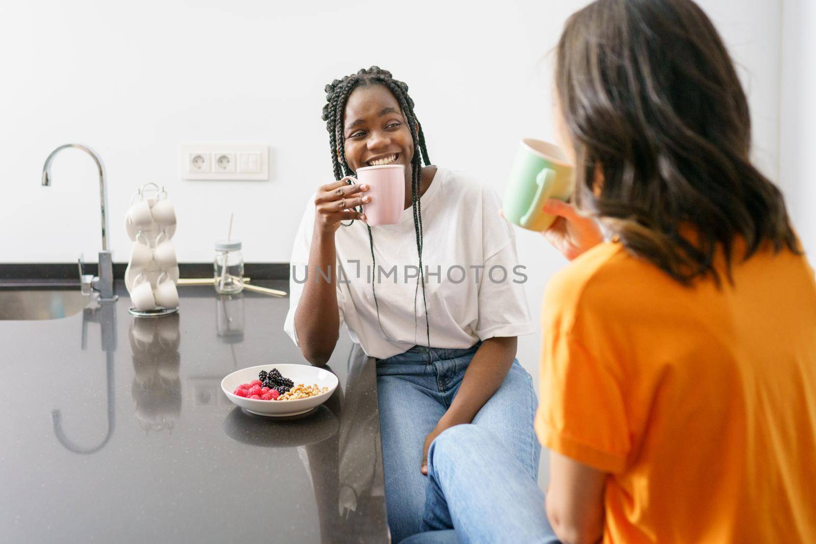 Two friends having a healthy snack while chatting at home. Multiethnic women.