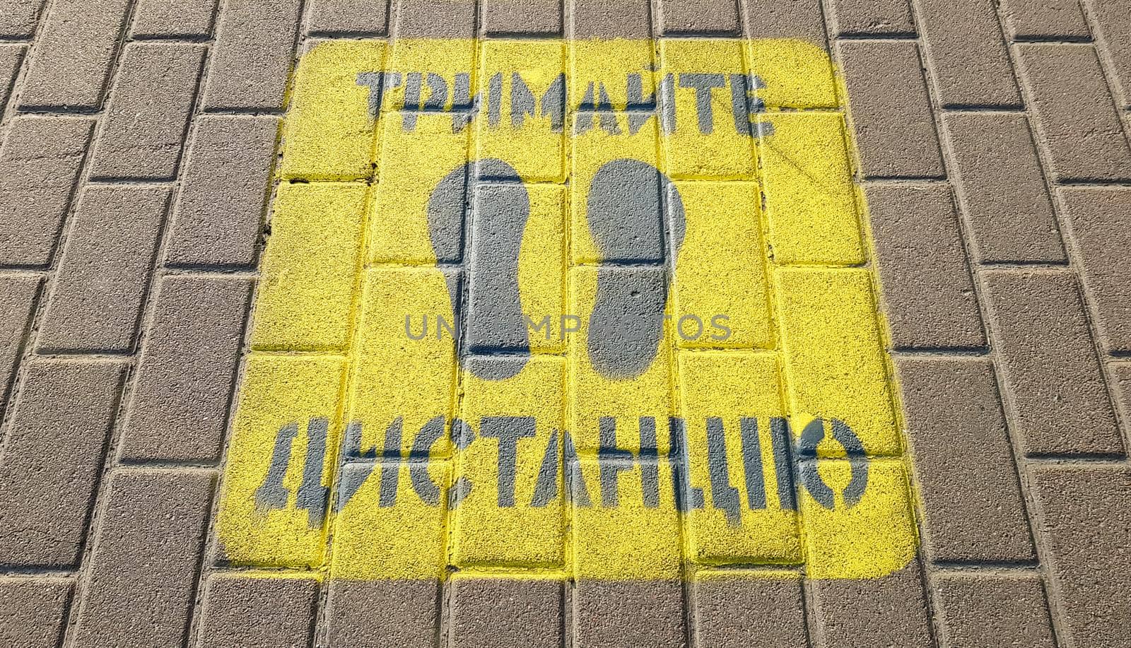 Ukraine, Kiev - April 23, 2020. Yellow sidewalk with the warning Keep your distance on the sidewalk. The text is in Ukrainian. Concept of maintaining social distance, quarantine or isolation by Roshchyn