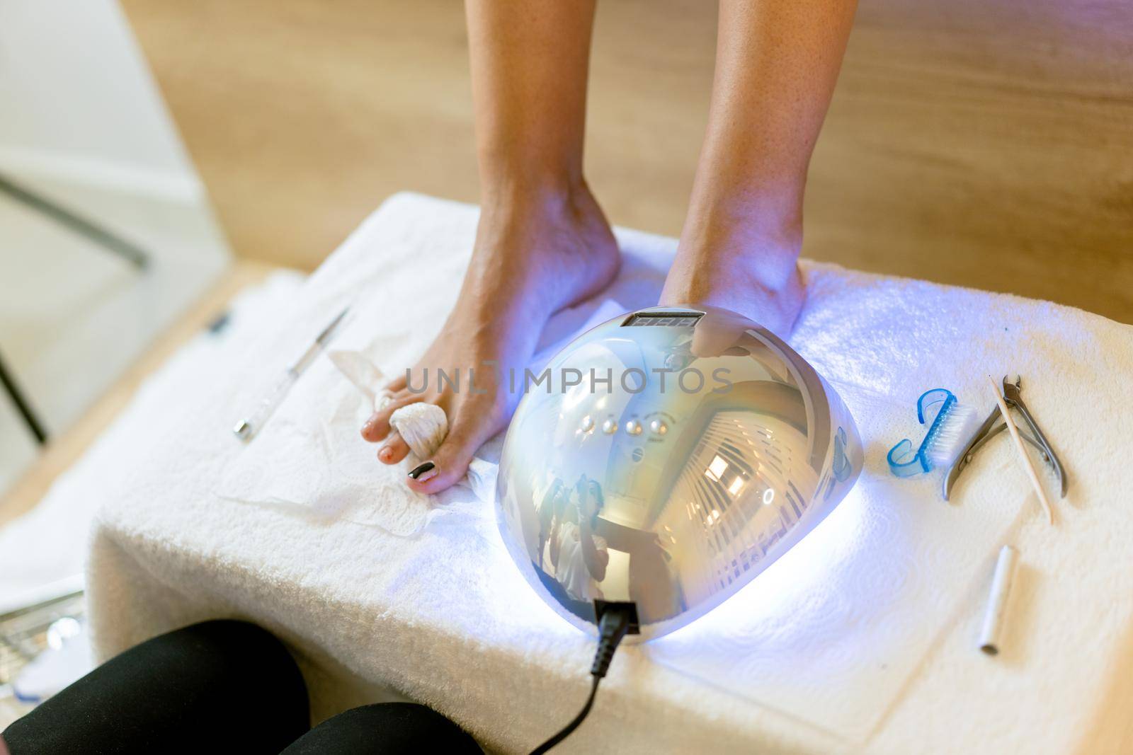 Beautician giving a pedicure painting her client's nails in a beauty centre. Business and beauty concepts