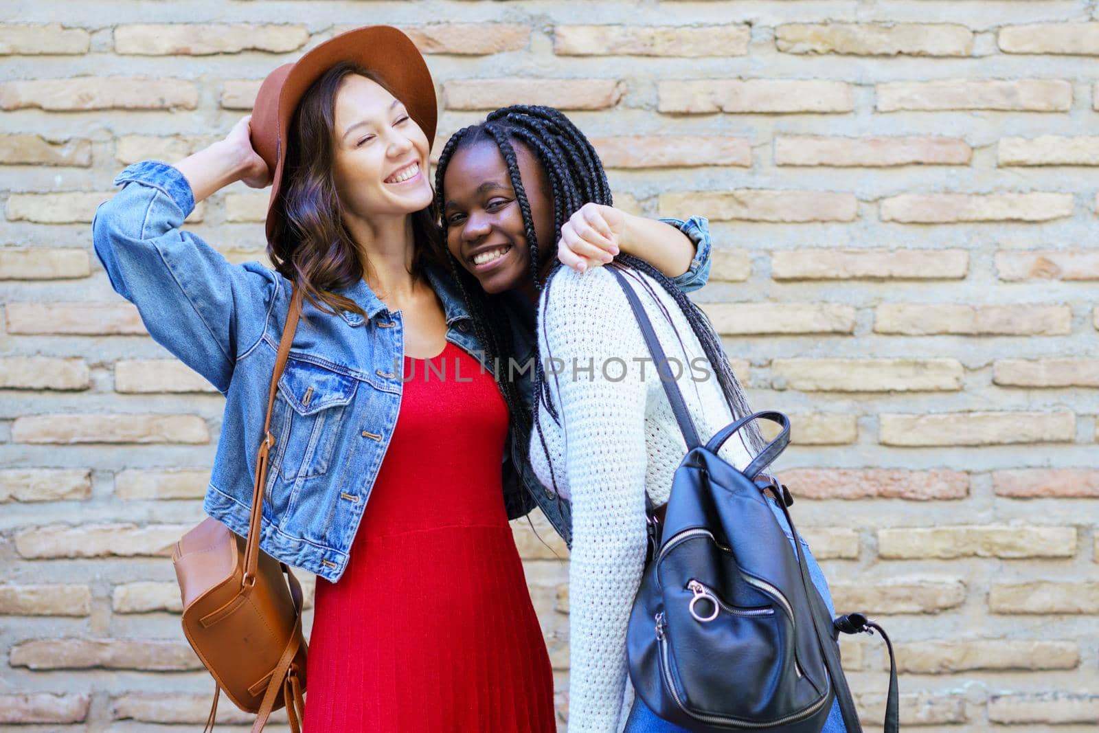 Two friends hugging in urban background. Multiethnic women.