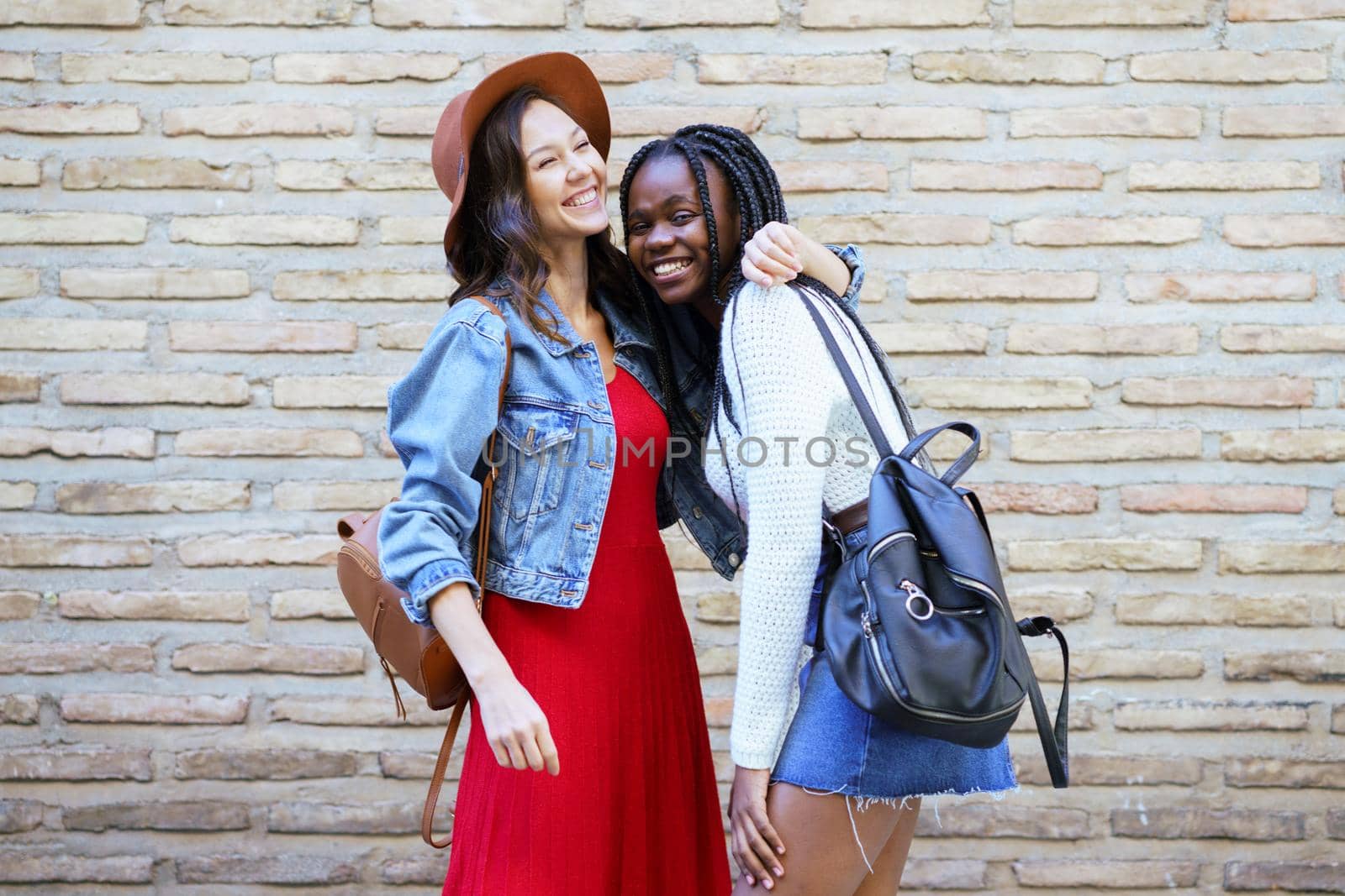 Two friends hugging in urban background. Multiethnic women.