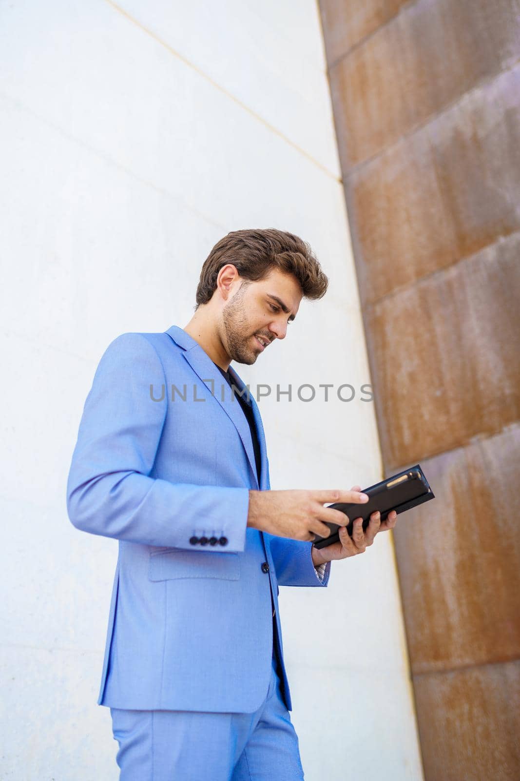 Young businessman using a digital tablet near an office building