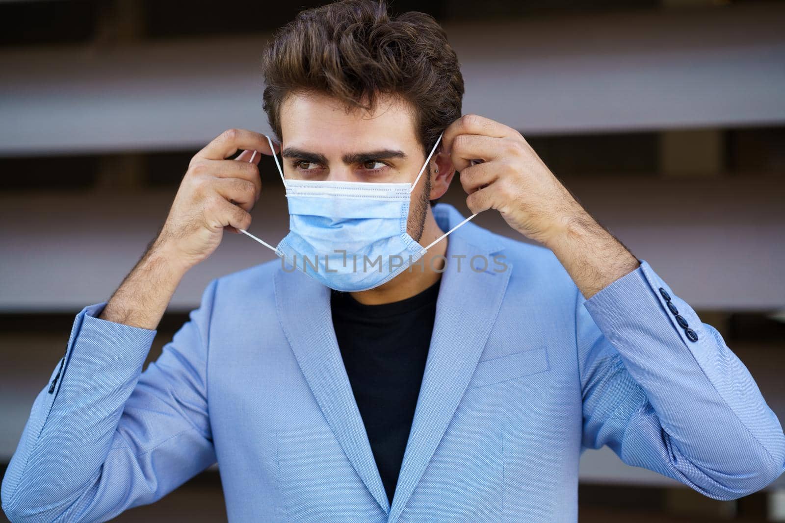 Caucasian businessman putting on a surgical mask to protect against the coronavirus.