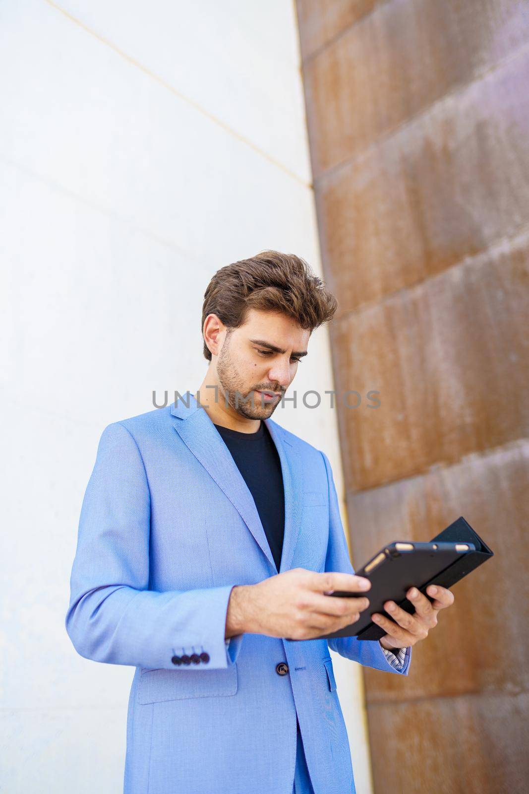 Man in a suit using a digital tablet outdoors
