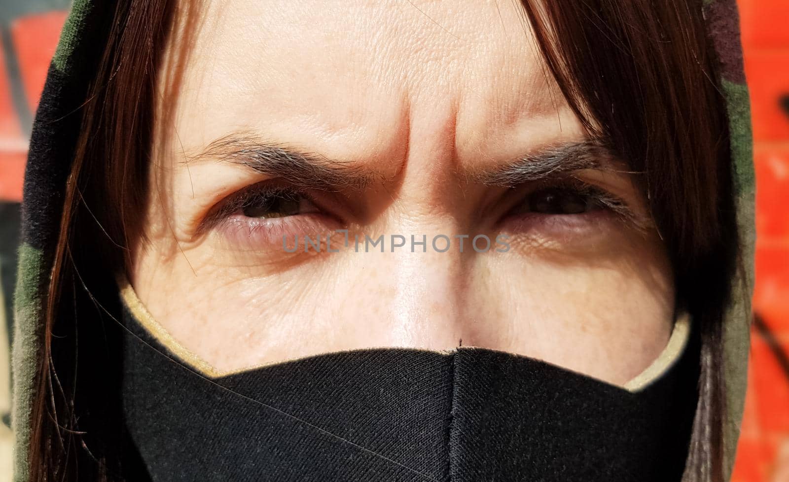 Portrait of a woman in a protective black mask outdoors near an old broken wall. Coronavirus and air pollution concept. A girl wears a protective mask to protect against a pandemic