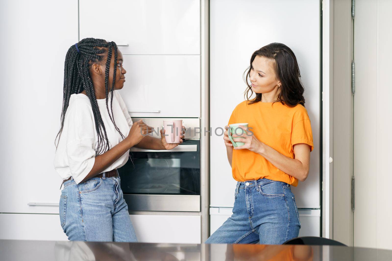 Two student friends taking a coffee break together at home Multiethnic women.