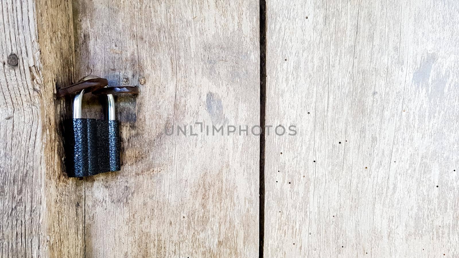 Old vintage metal padlock on a closed wooden door of an old farmhouse. The true style of the village. close-up. focus on the castle. Wooden background, texture. Copy space.