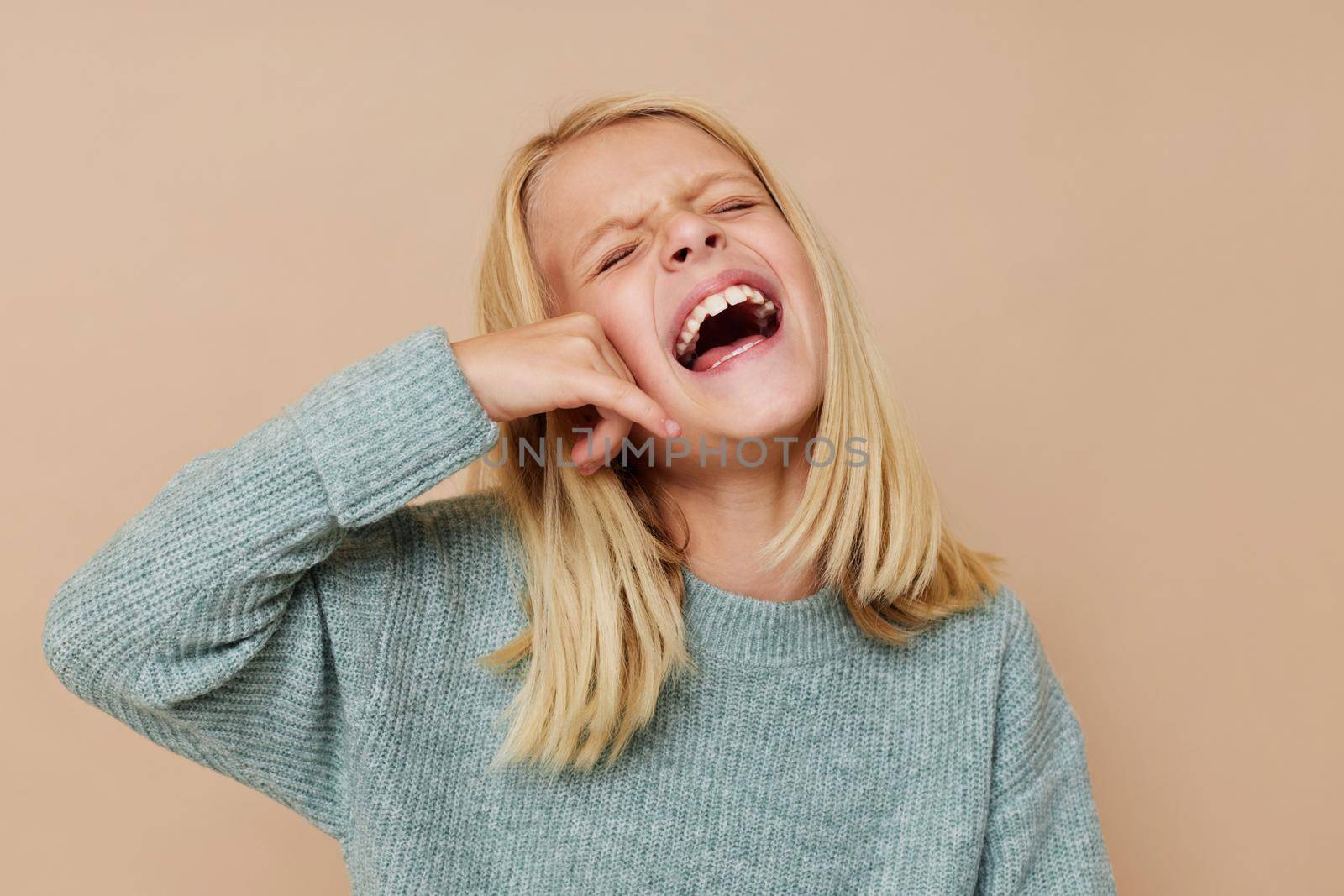 Little cute girl in a sweater, grimaces cropped view. High quality photo