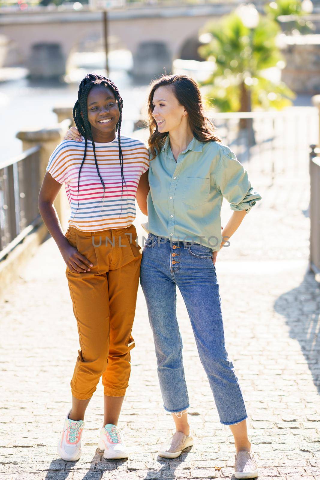 Two friends walking together on the street. Multiethnic women.