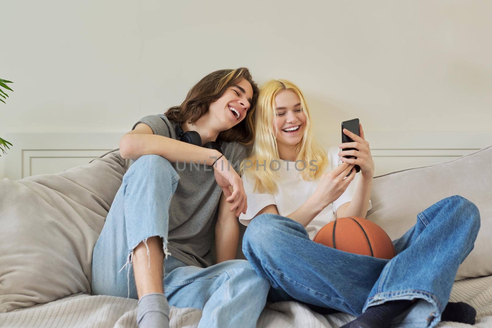 Happy laughing hipster teenagers male and female having fun using smartphone by VH-studio