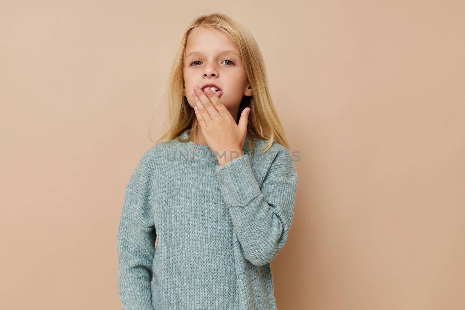 Portrait of a smiling little cutie in a sweater, grimaces on a light background by SHOTPRIME