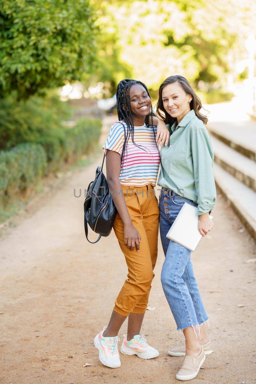 Two multiethnic female friends posing together with colorful casual clothing outdoors. Mutliethnic women.