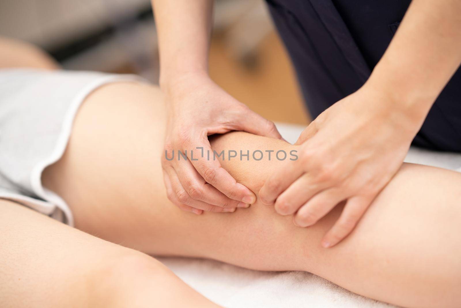 Female Physiotherapist woman doing a treatment on a young woman's knee.