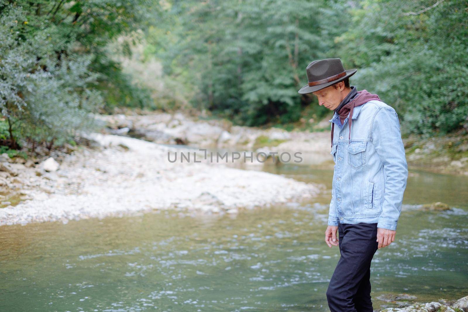 Fashionable explorer man walking by the river. by alexAleksei