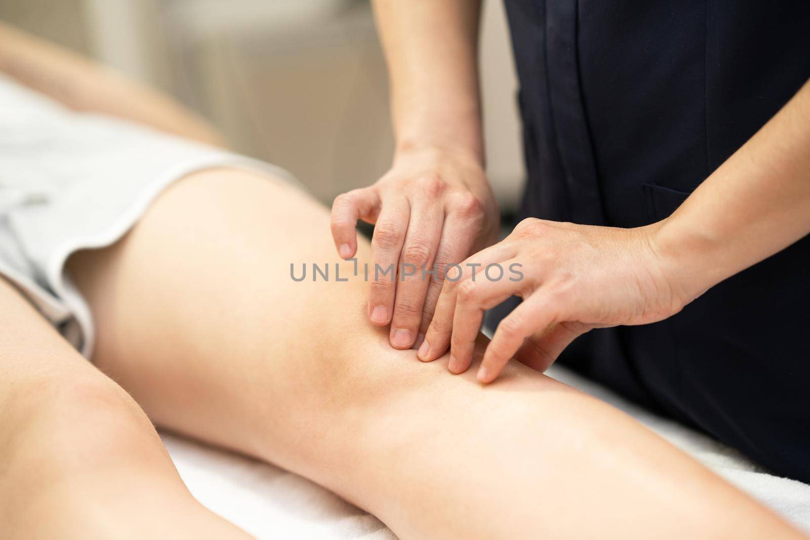 Female Physiotherapist woman doing a treatment on a young woman's knee.