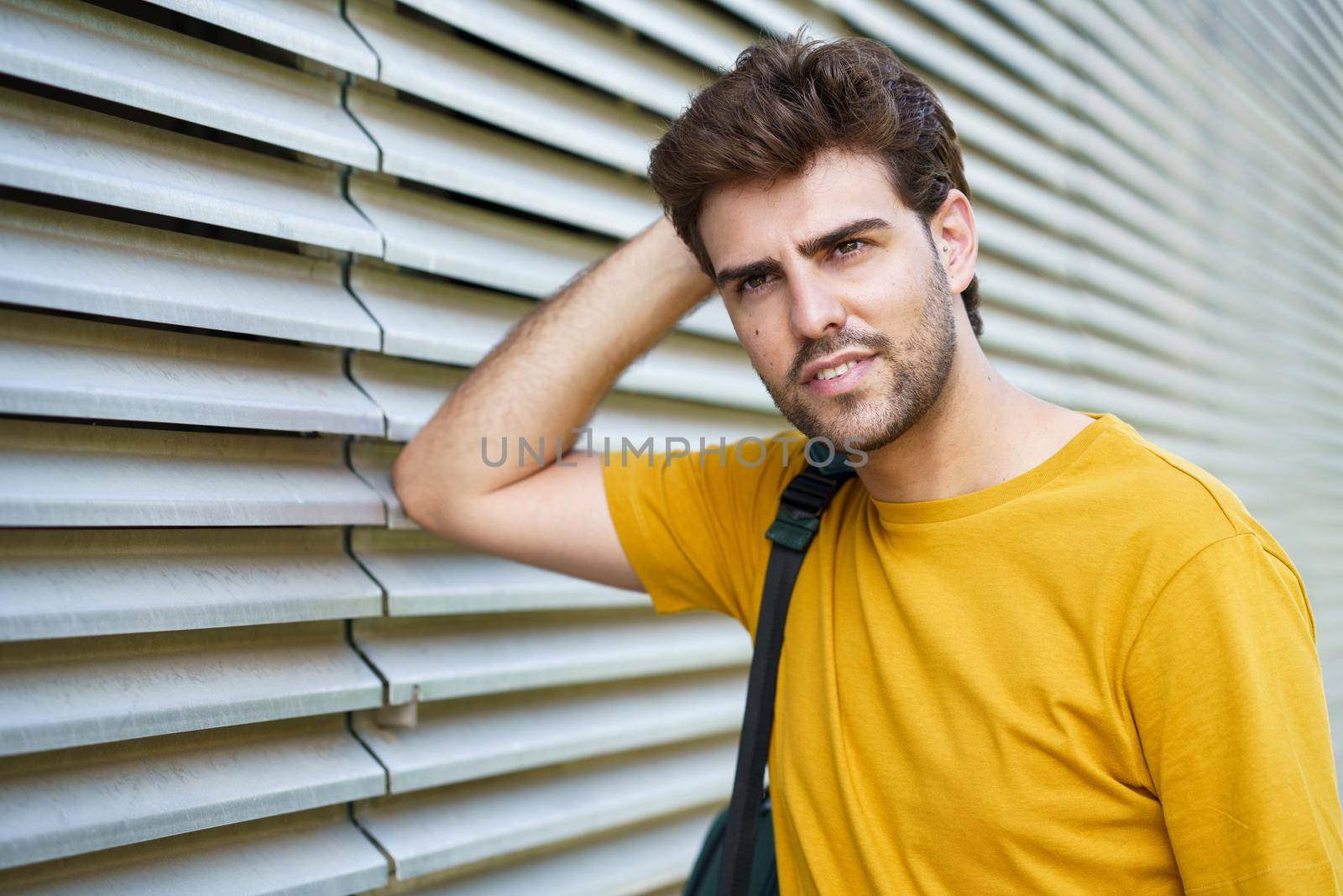 Portrait of young man with modern haircut looking away in urban background