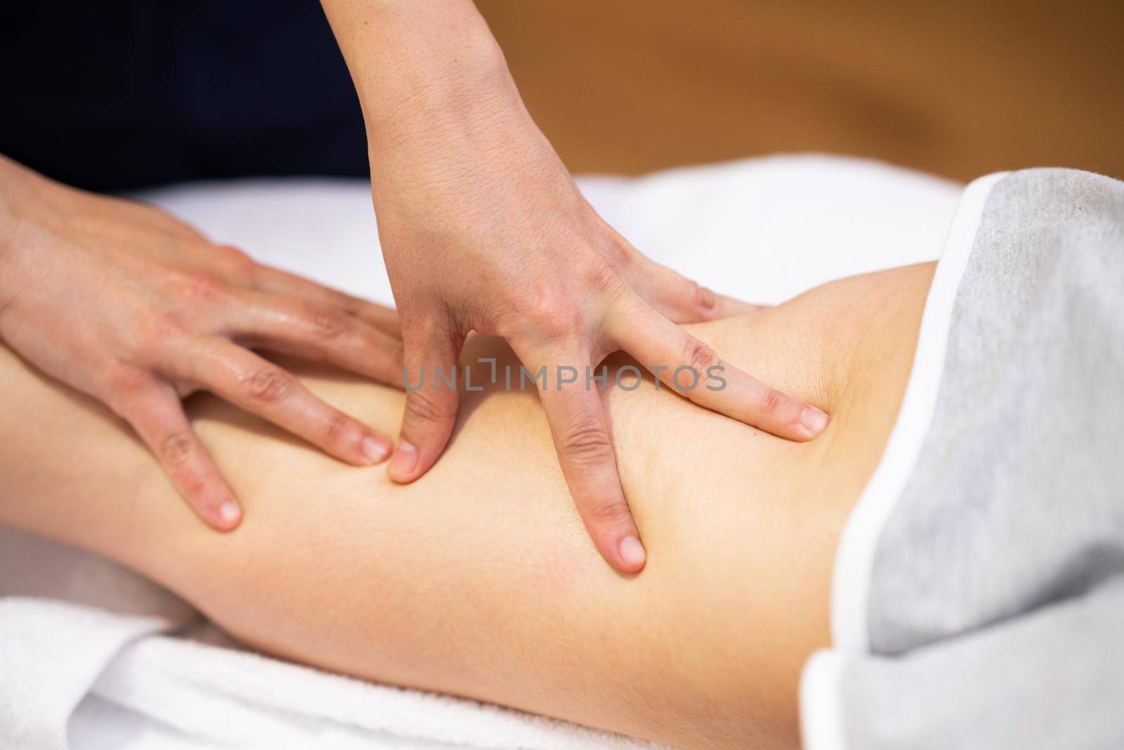 Medical massage at the leg in a physiotherapy center. Female physiotherapist inspecting her patient.