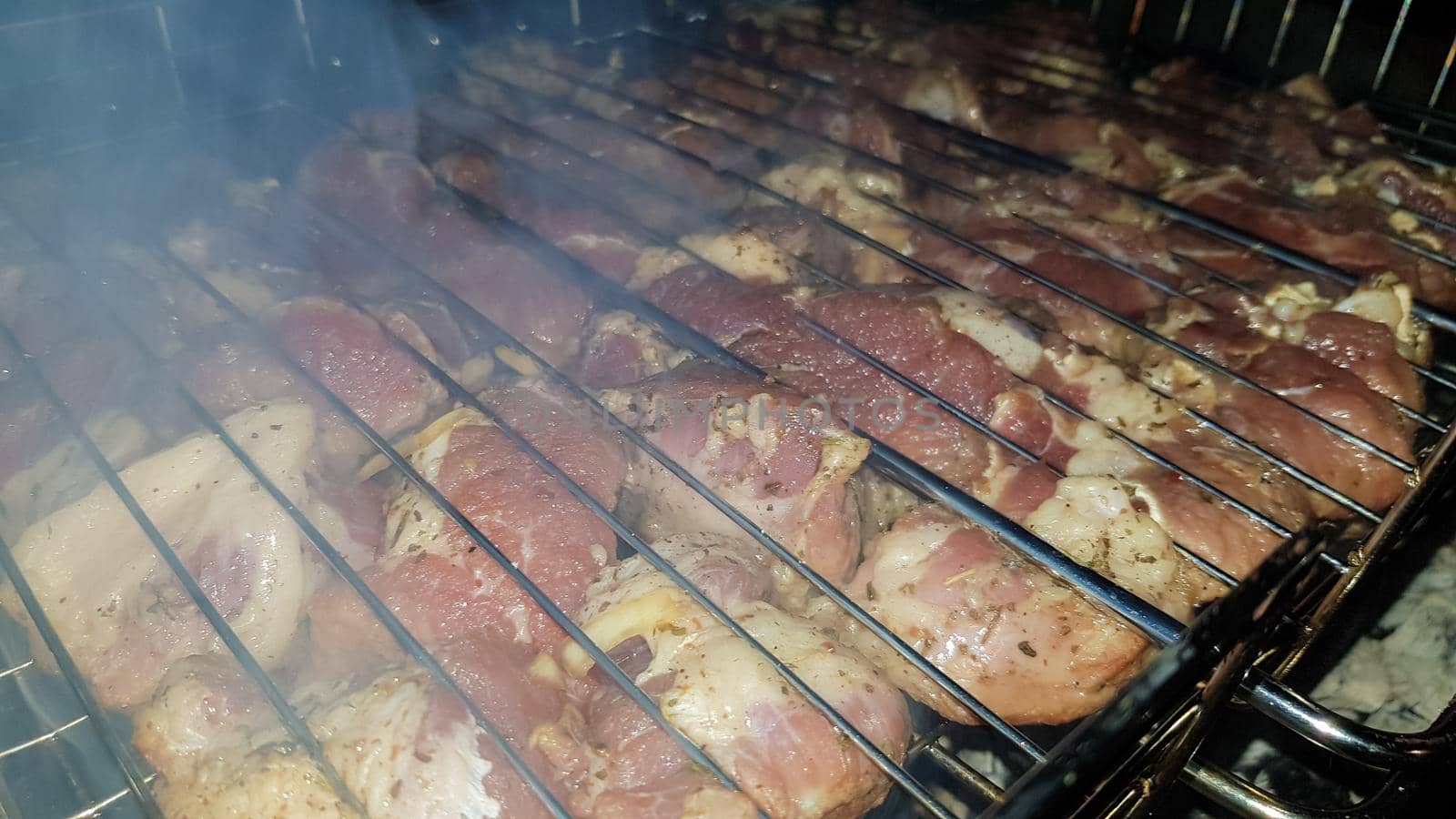 The process of cooking shish kebab on the grill. Juicy and fragrant meat languishes on fire and smoke. Countryside picnic concept at night. Appetizing and nutritious picnic dish in the open air
