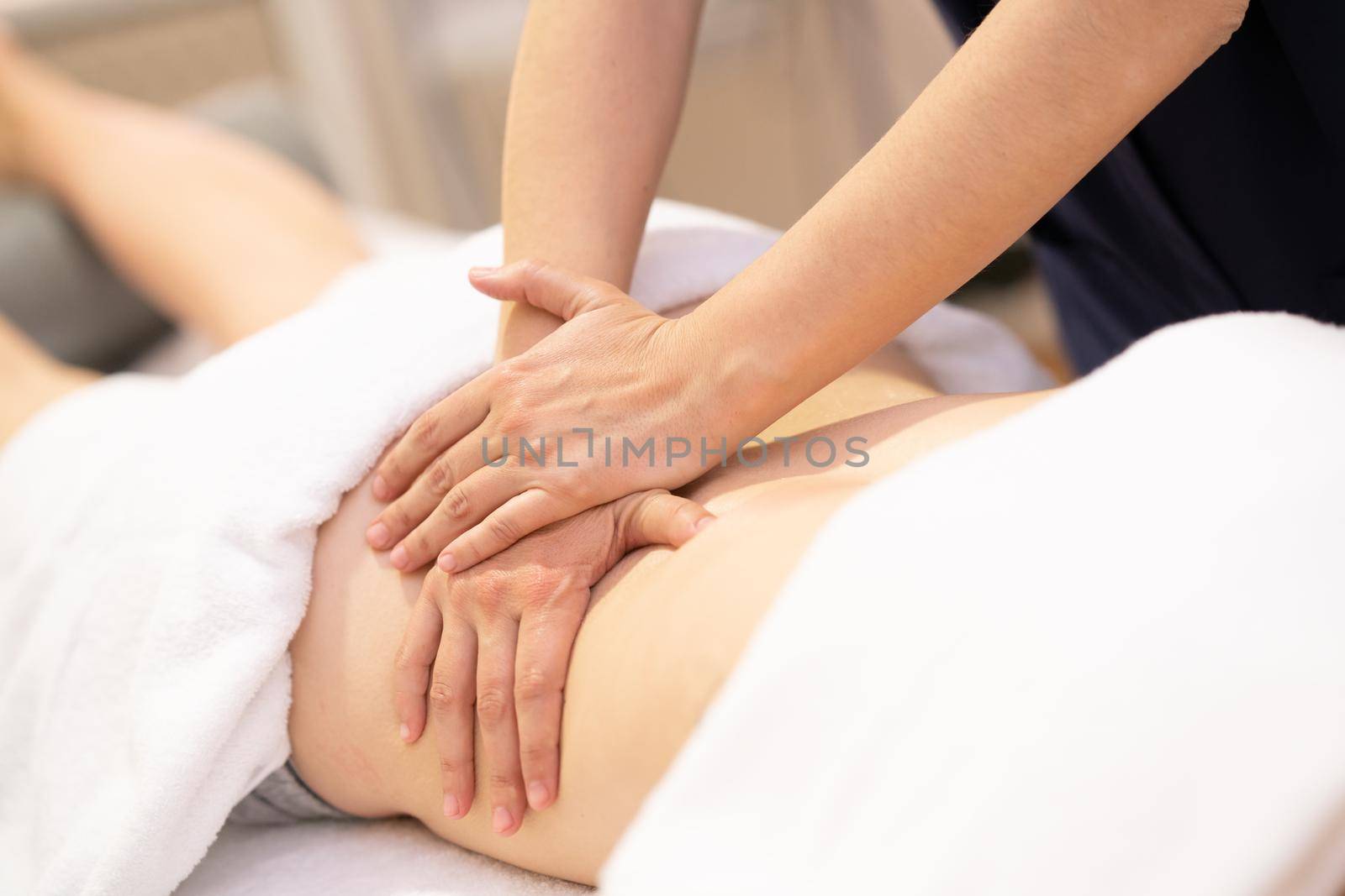 Young woman receiving a back massage in a physiotherapy center. Female patient is receiving treatment by professional therapist.