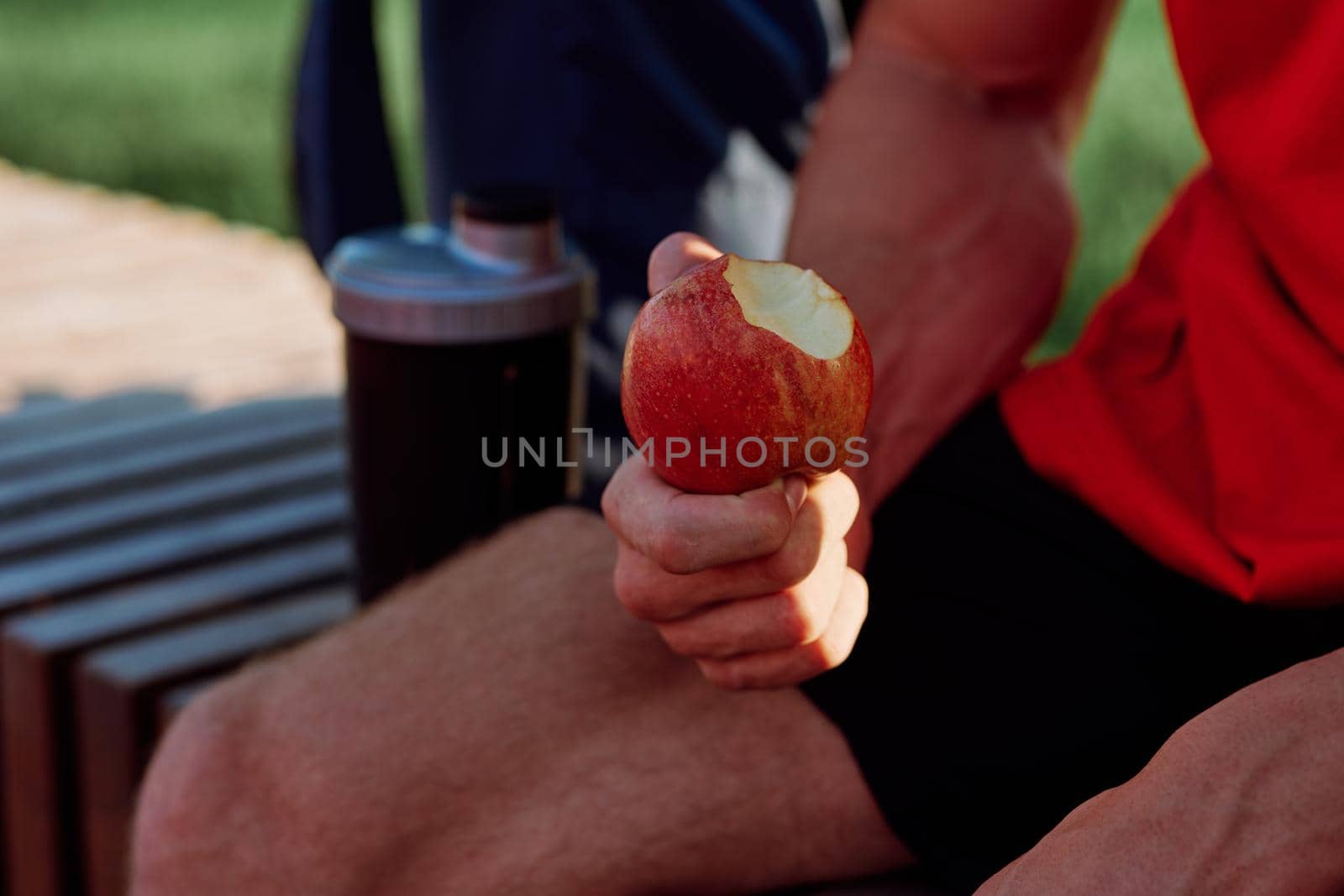 sporty man resting in the park on a bench having a snack by Vichizh