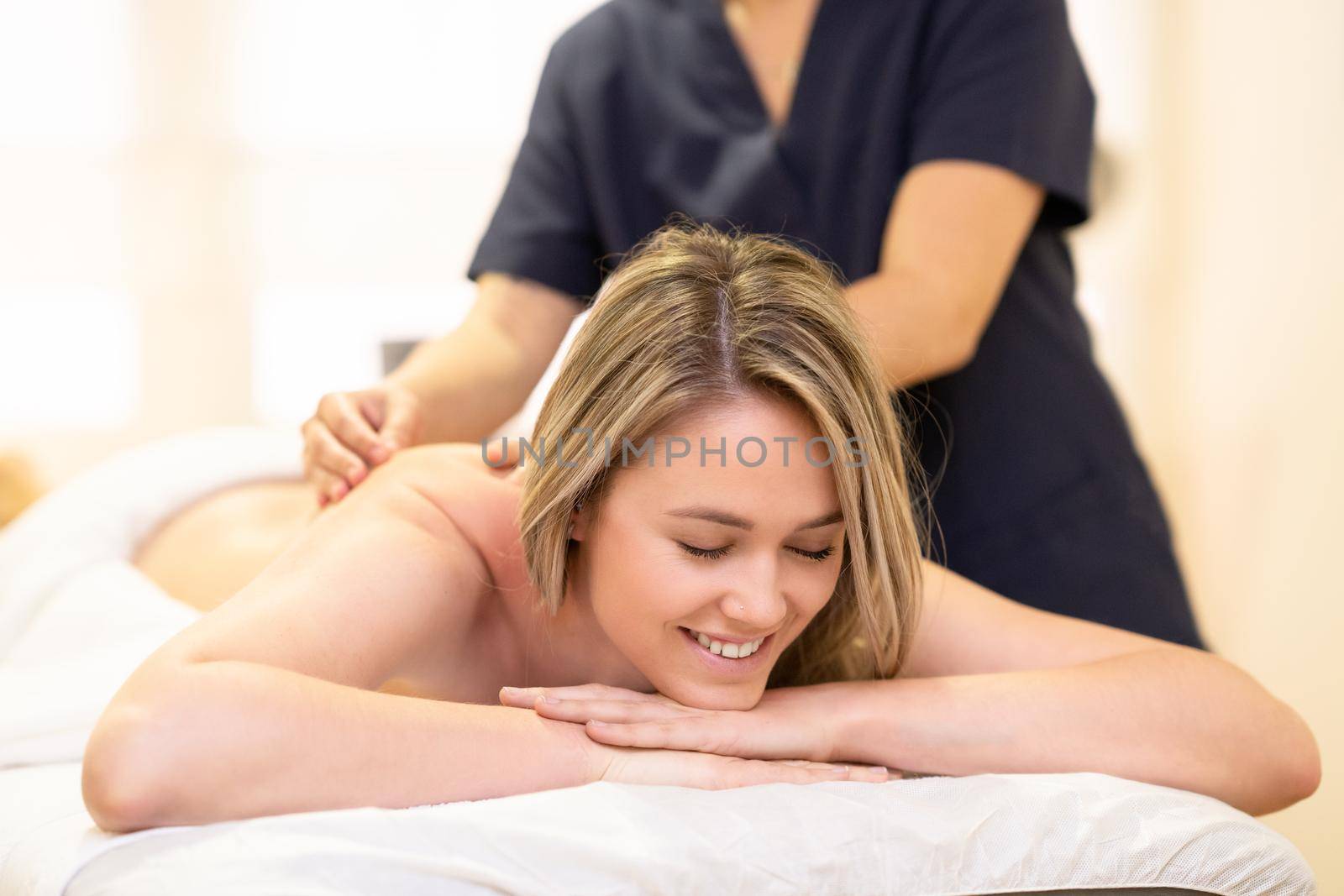 Young woman lying on a stretcher receiving a back massage in a spa center.