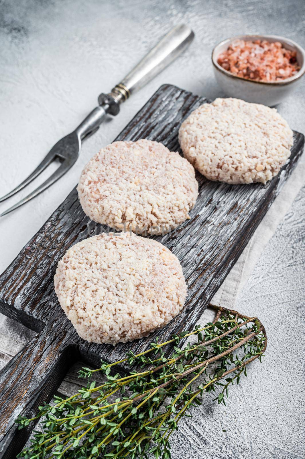 Raw meat patty cutlets with breadcrumbs on wooden cutting board. White background. Top view.