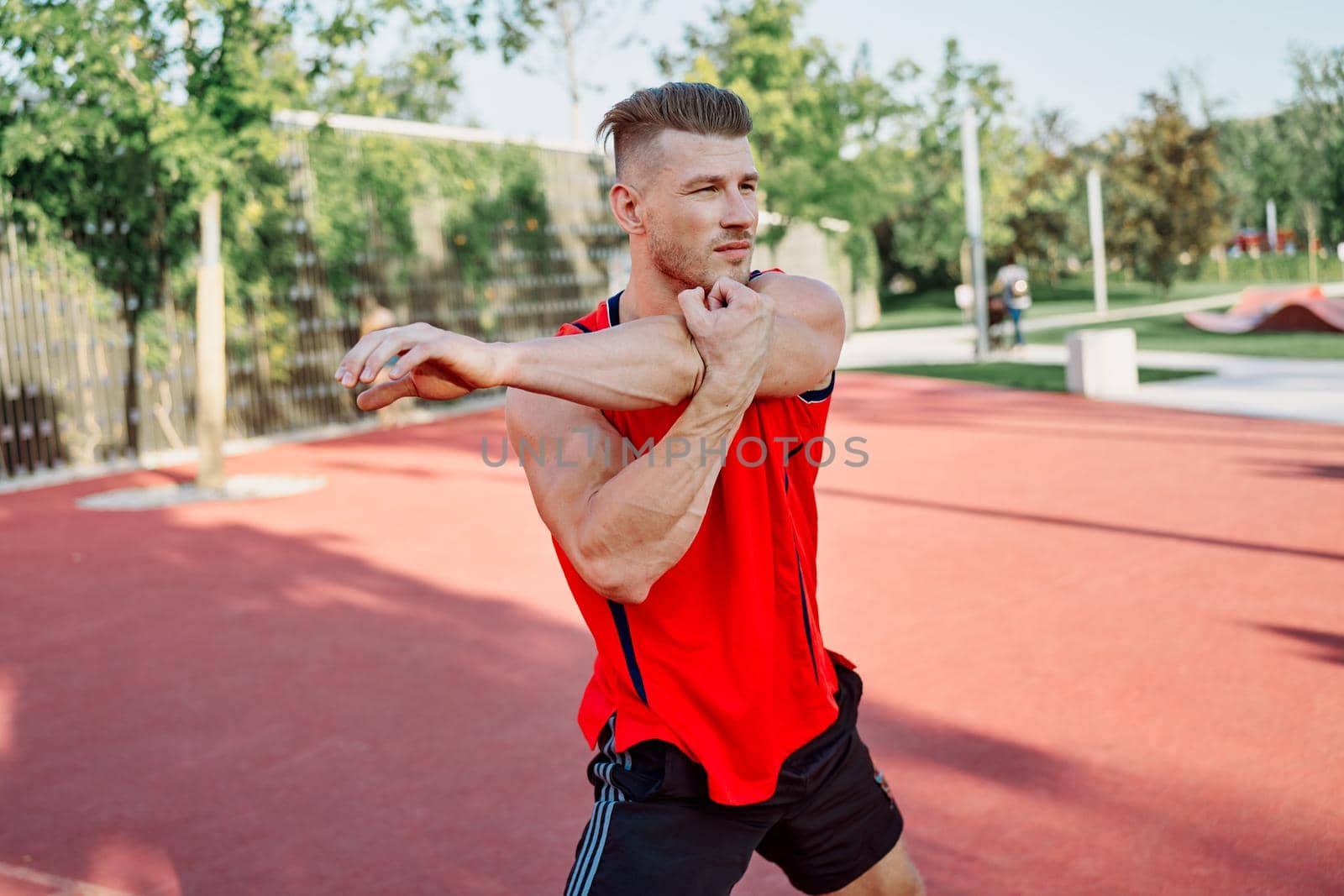 sports man in a red t-shirt on the sports ground doing exercises. High quality photo