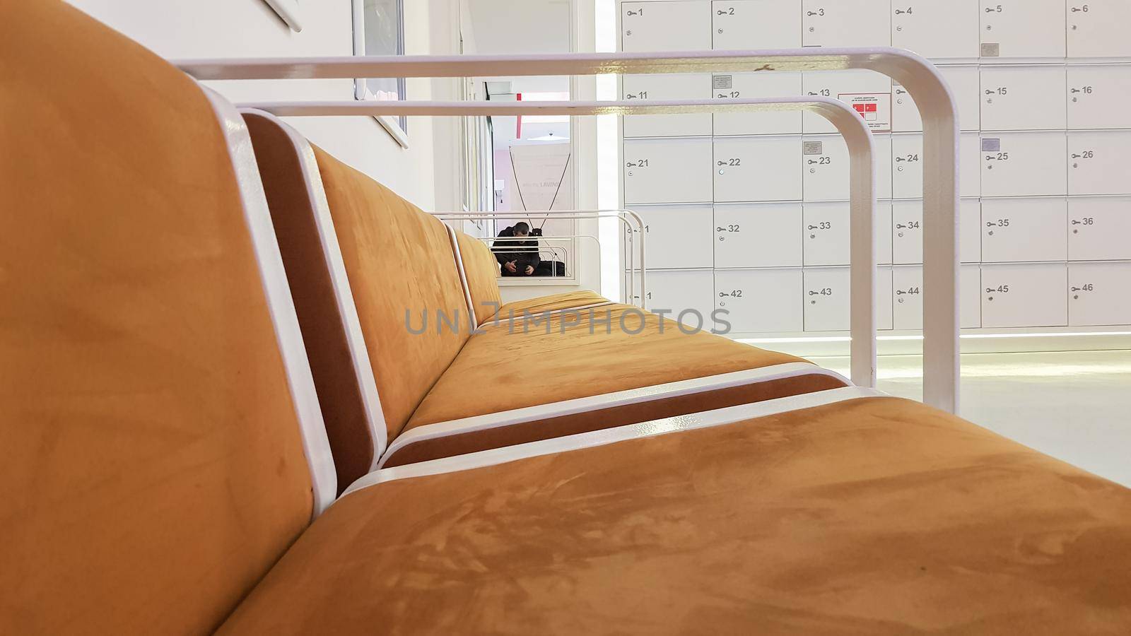 close-ups of benches upholstered in brown suede or leather with white metal railing in a cinema waiting room in a shopping center by Roshchyn