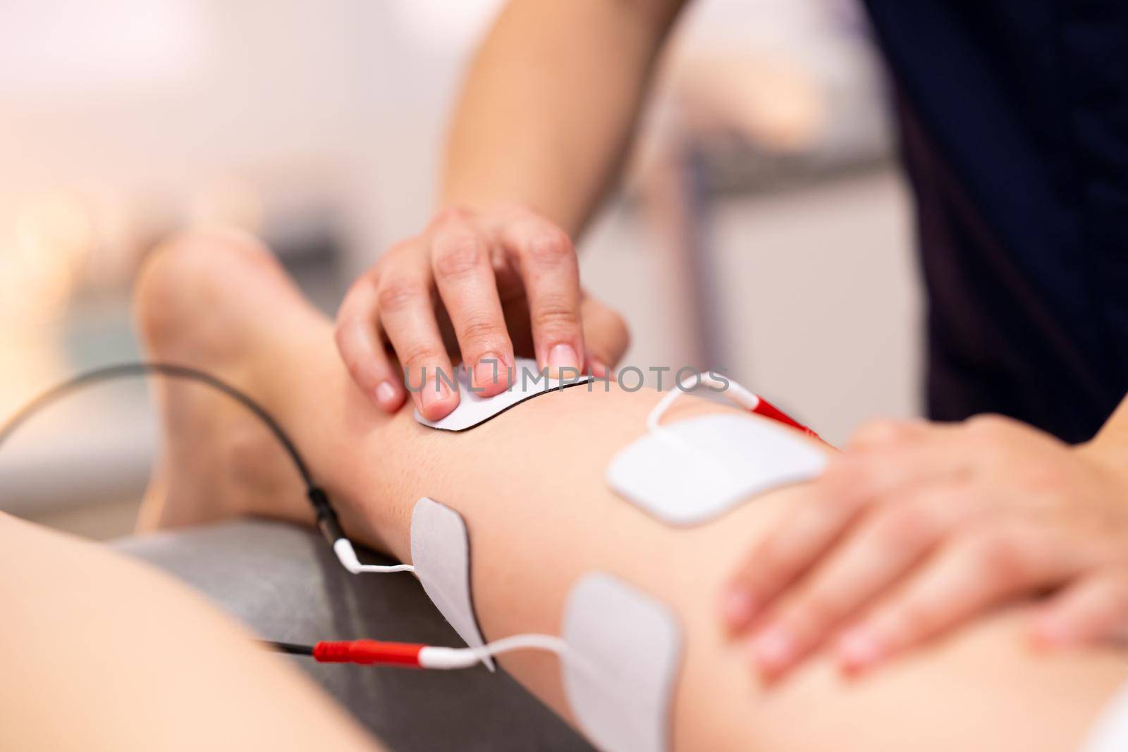 Physiotherapist applying electro stimulation in physical therapy to a young woman.