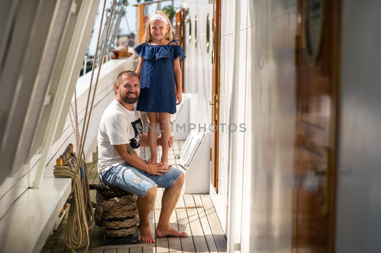 A little girl sits in the arms of a man on the deck of a large sailing ship in the city of Klaipeda, Lithuania