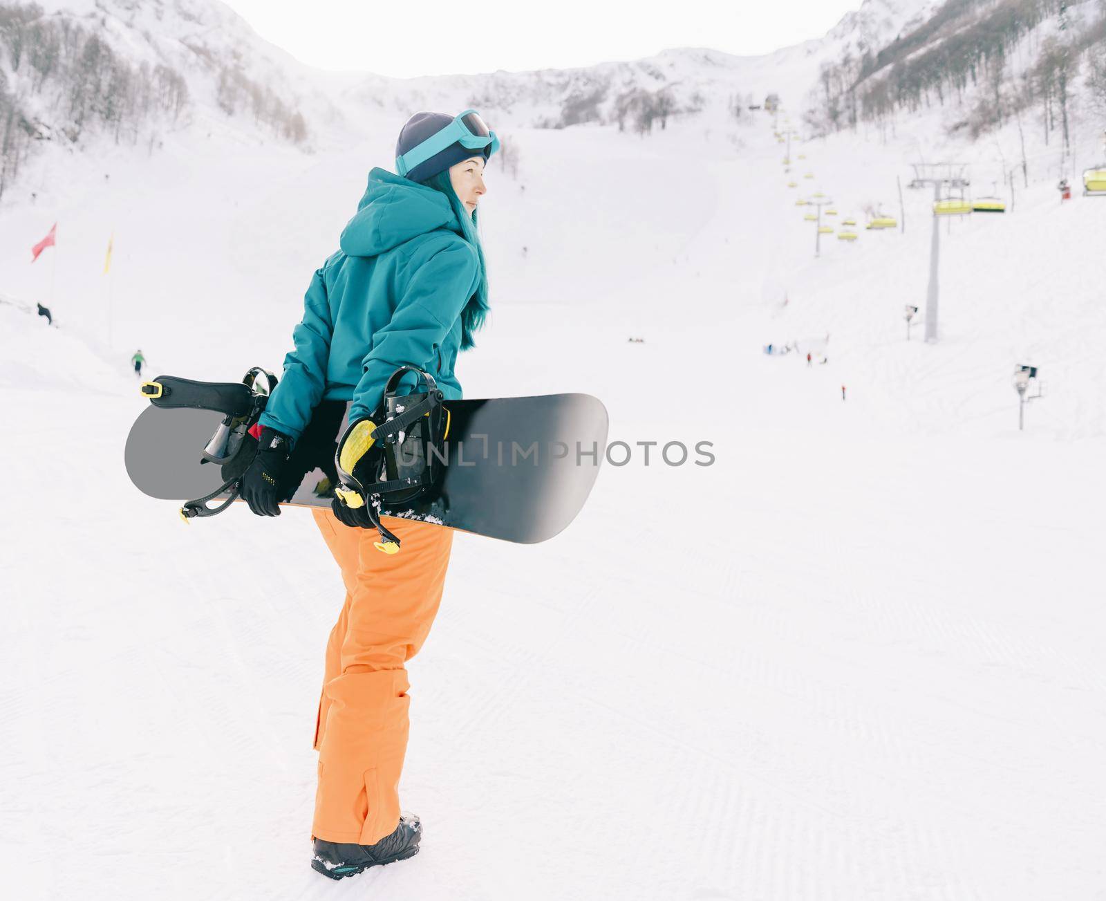 Sporty young woman walking with snowboard on ski resort in winter outdoor.