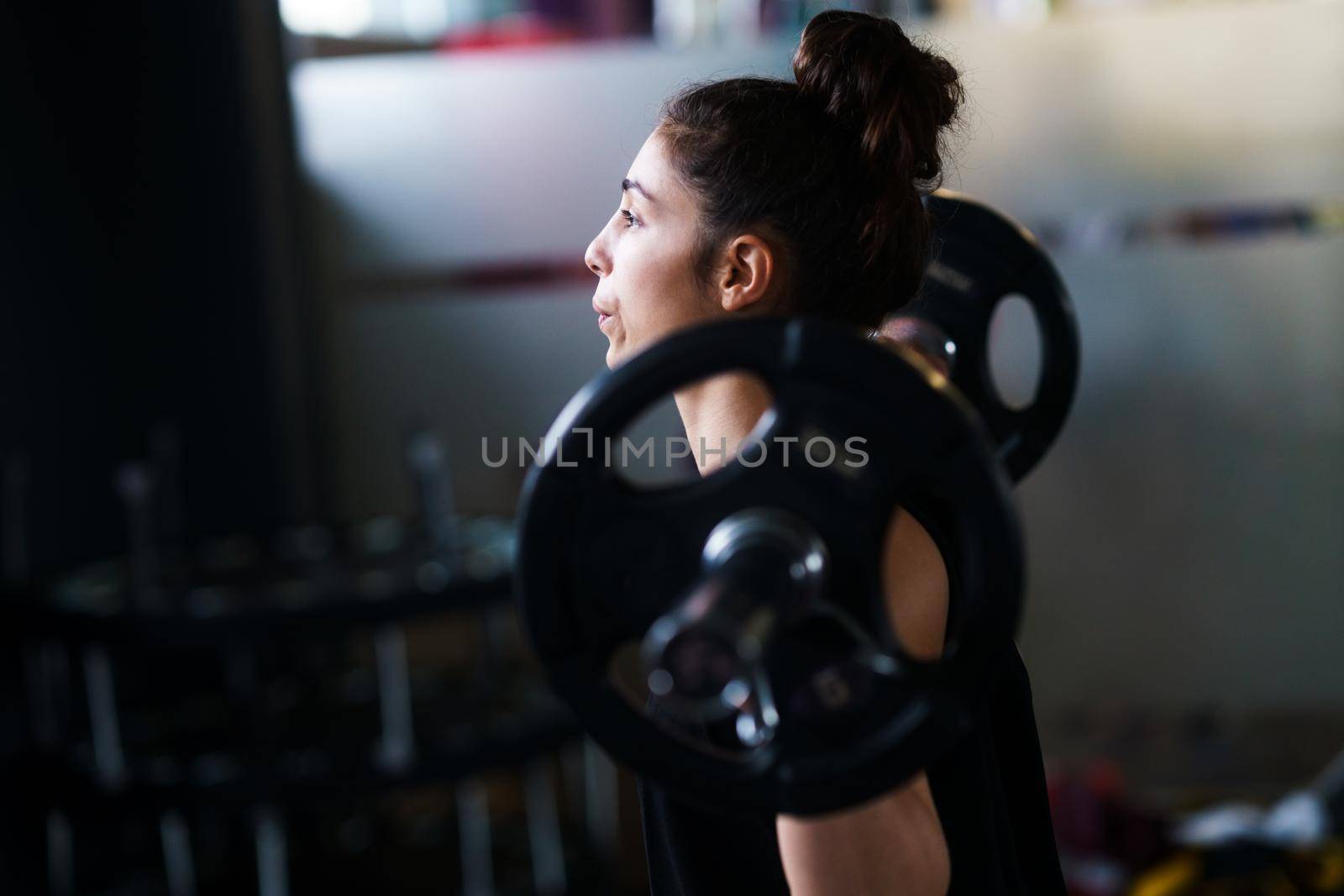 Athletic woman in gym lifting weights at the gym. Fitness concept.