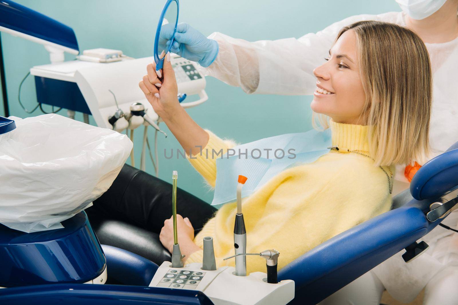 The girl smiles and looks in the mirror in dentistry by Lobachad