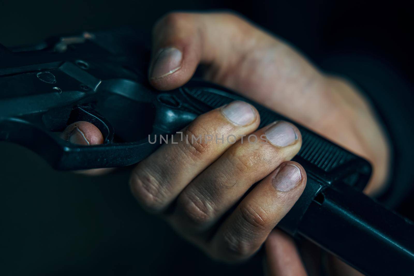 Man inserts drum of cartridges into pistol. Reloading gun close-up. Firearms in hand on dark background. Defense or attack.