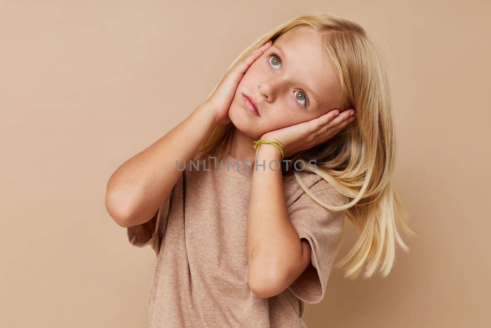 Beautiful little girl in a beige t-shirt posing studio by SHOTPRIME