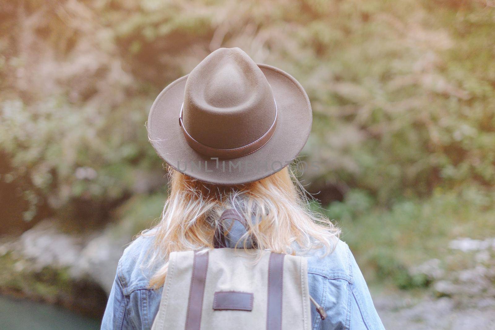 Explorer young woman with backpack walking in summer nature outdoor, rear view.