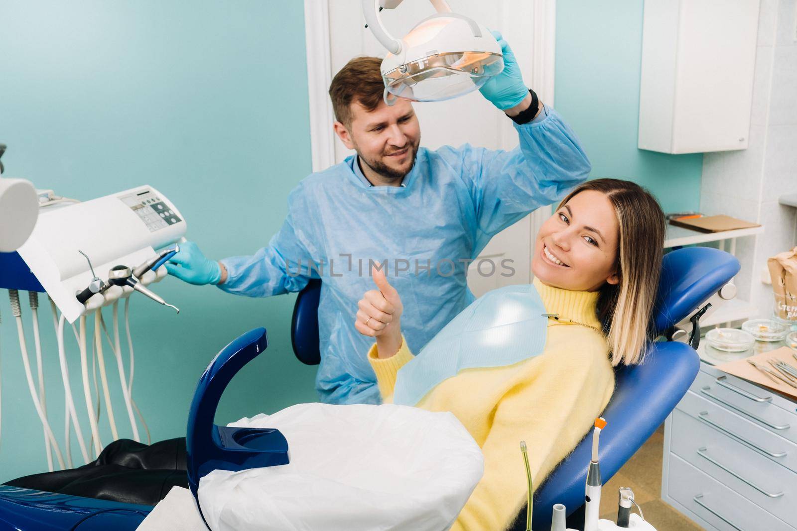 Beautiful girl patient shows the class with her hand while sitting in the Dentist's chair by Lobachad