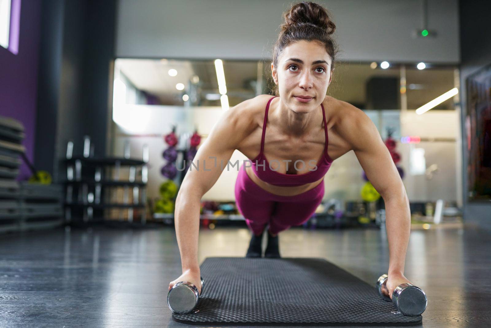 Woman doing push-ups with dumbbells in a fitness workout