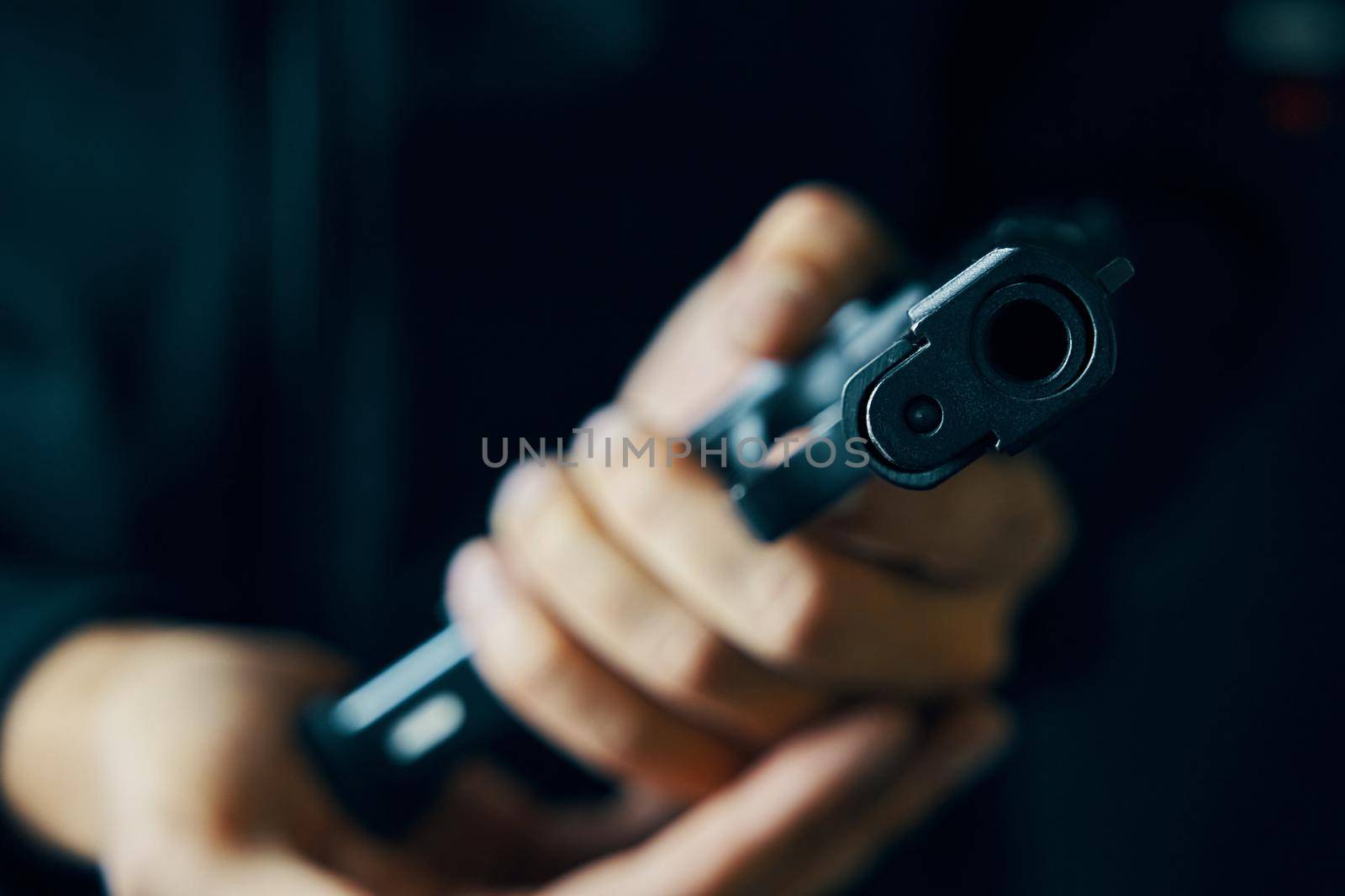 Muzzle of gun close-up. Man reloading pistol. Weapon ammunition. Firearms in hand on dark background. Defense or attack.