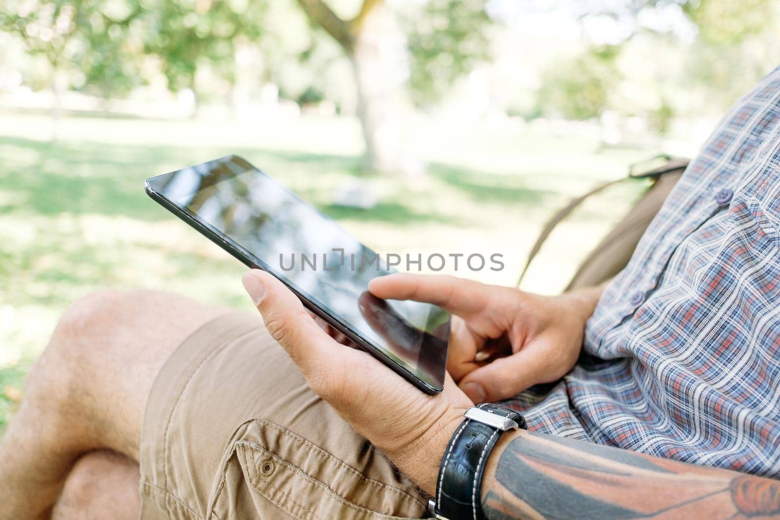 Unrecognizable young man student using with digital tablet in the park.