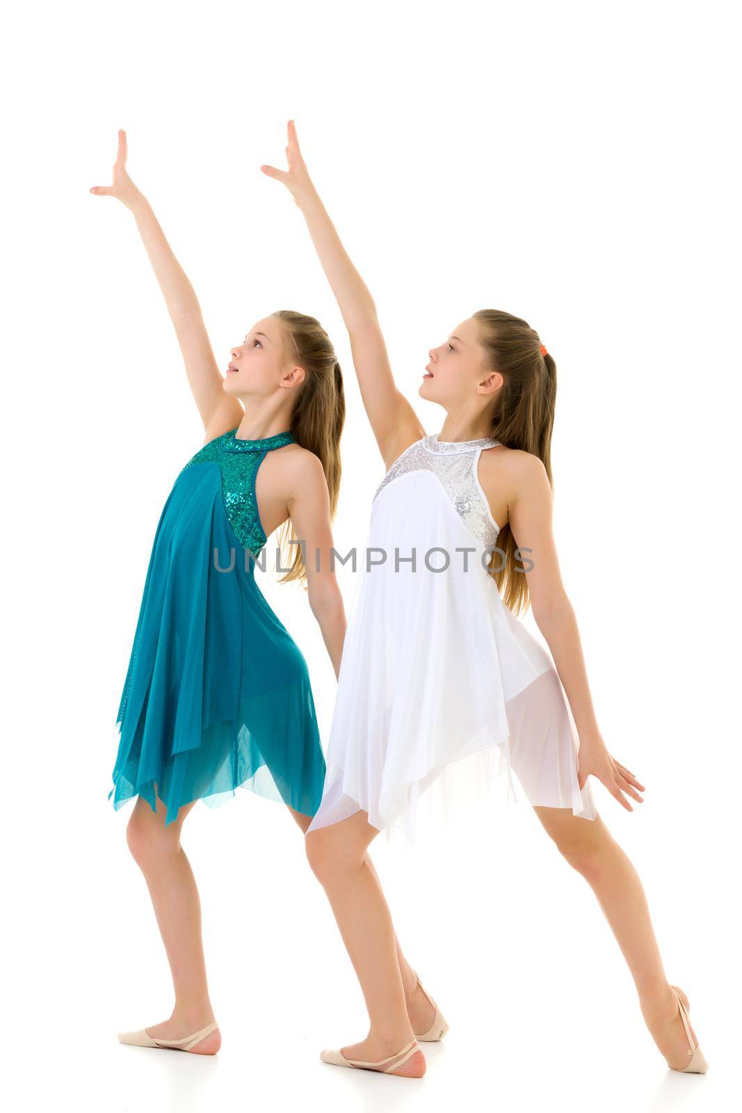 Pretty Girls Dancers Dancing Synchronously in Studio, Two Beautiful Twin Sisters Wearing White and Blue Sport Dresses Performing Together, Two Teenage Girls Posing in Studio Against White Background
