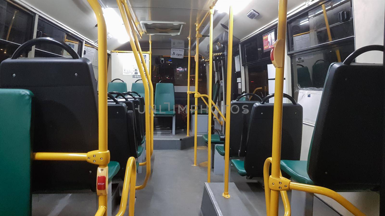 An empty bus is equipped with handrails for holding it on the inside. Modern land-based suburban and urban public passenger transport in the city. Passenger seats. by Roshchyn